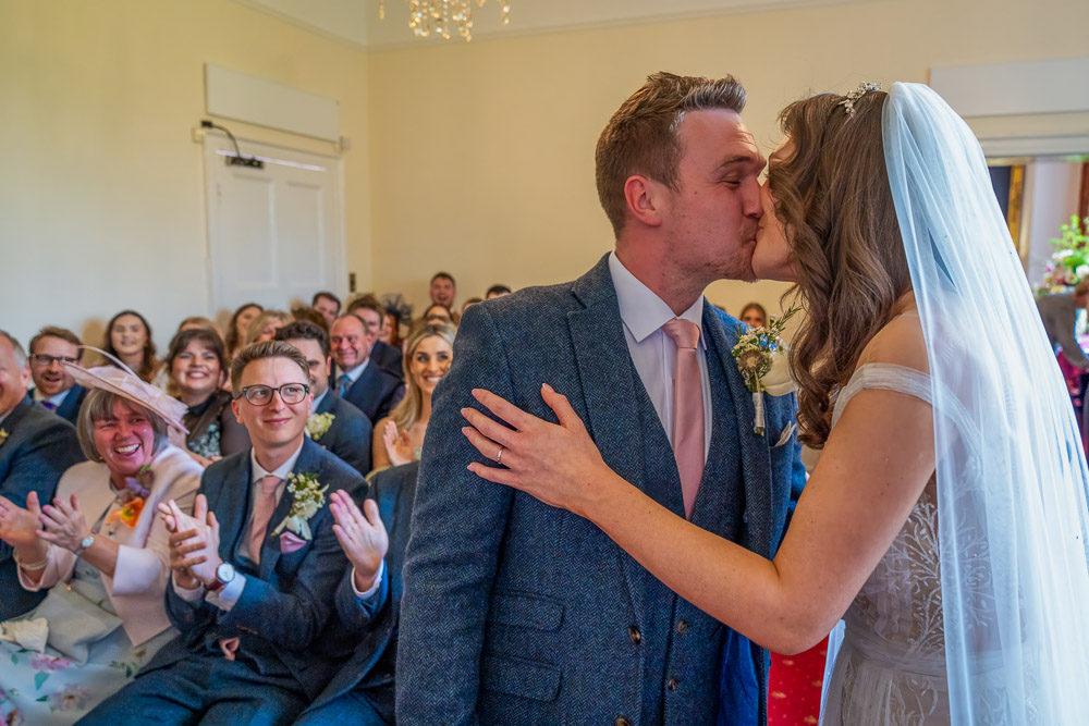 A brighter image of the bride and groom as they kiss in front of their guests after saying their vows.
